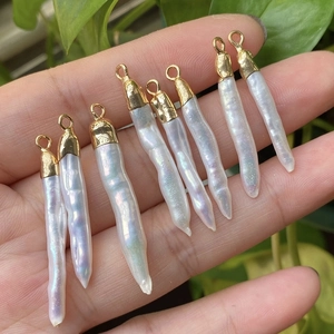Eight rectangular baroque pearls with gold-plated metal caps held in hand