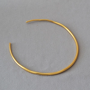 Top view of minimalist gold plated irregular open choker necklace on grey background