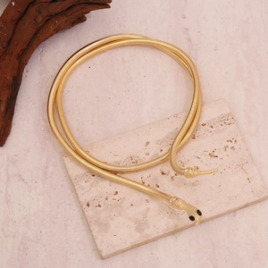 Dettaglio della collana a serpente dorata con testa incisa e piccoli occhi neri lucidi