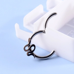 Detailed view of a silver snake-shaped hinged piercing ring on a display stand