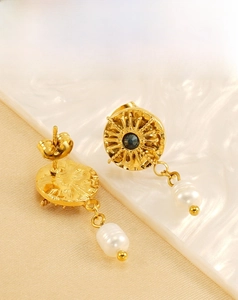 Detailed close-up of vintage gold starburst earrings with dark stone and pearl charms