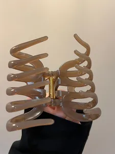 Detail of a large brown acrylic hair claw clip with golden metal spring for thick hair