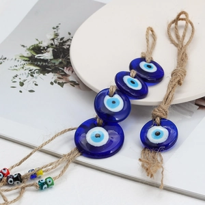 Dettaglio di ciondoli Evil Eye in vetro blu con corda di canapa su piatto di ceramica