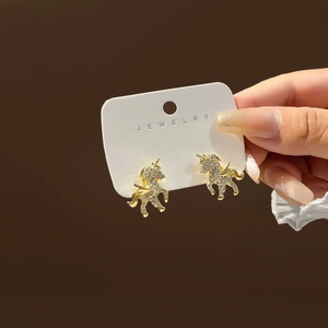 Sparkling gold unicorn stud earrings with zircon stones held on a jewelry card
