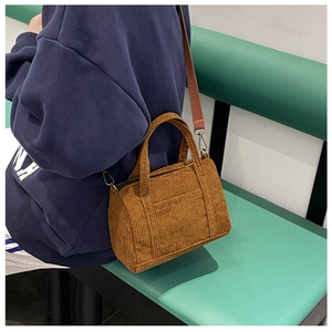 Detailed texture of brown corduroy Boston bag with adjustable shoulder strap and side pocket