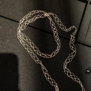 Detailed view of long gold braided necklace with intricate mesh woven texture