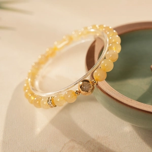 Macro detail of yellow citrine bead bracelet with golden flower charm and zircon spacers
