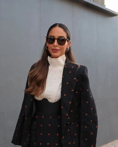 Gros plan sur la veste de costume noire brodée de fraises et le pull à col roulé blanc