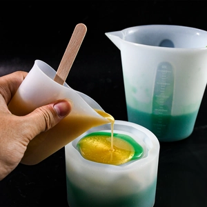 Detail of 500ml silicone measuring cup showing scale marks and yellow resin pouring process