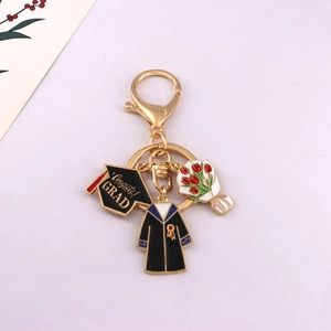 Close-up of golden graduation keychain with mini black mortarboard and red bouquet charms