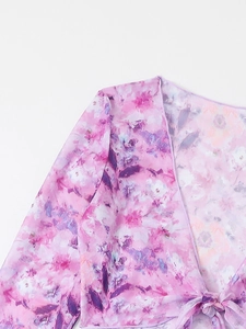 Close-up detail of sheer pink floral wrap top with V-neck and delicate printed texture