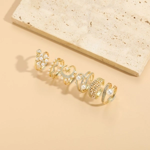 Detail of six gold plated rings with pearls and cubic zirconia on a stone stand