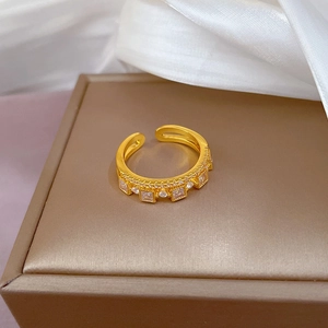 Adjustable gold open ring with square and round zircons on white silk backdrop
