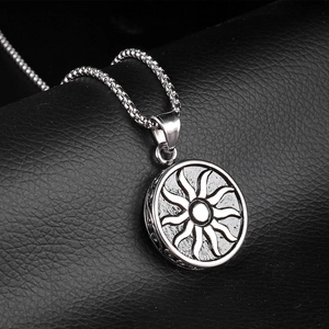 Silver round sunburst totem pendant necklace for men on a black textured surface