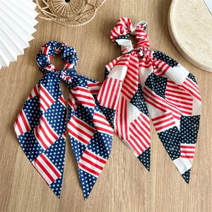 Detail of two American flag bow scrunchies with long ribbons on a wooden surface