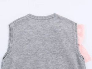 Close-up of the grey knitted vest featuring pink ruffled shoulder detail and round neckline
