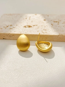Detail view of water drop earrings in matte gold finish with brushed metal texture