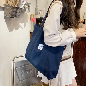 Macro shot of dark blue canvas tote bag showing stitching and woven label detail