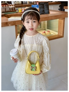 Close-up of yellow PU leather bag with green buckle and bow on white star dress