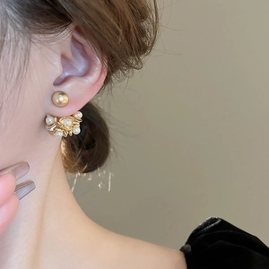 Detail view of vintage gold flower ear jacket with pearls on elegant model's earlobe