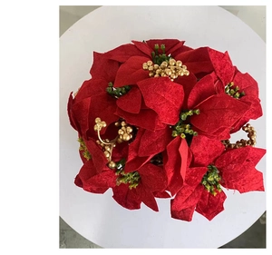 Detail view of red velvet poinsettia flowers with gold berries and green leaves