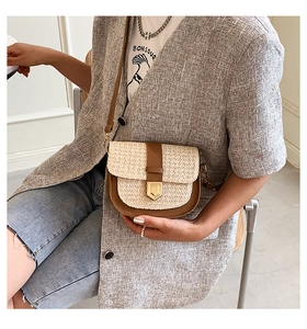 Detail of hand-woven straw and brown leather stitching on a small saddle crossbody bag