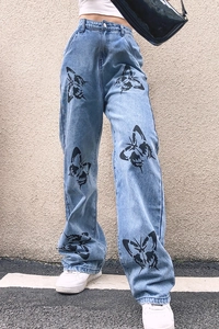 Detail of high-waist blue denim trousers featuring artistic black butterfly print patterns