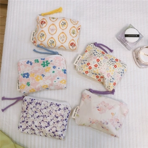 Flat lay of small floral zipper pouches with woven pulls and simple wish label