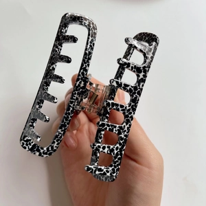 Detail of large acetate hair claw clip featuring black and white spotted animal patterns