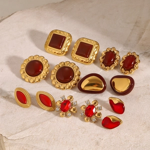 Macro detail of vintage gold earrings set with red stones on natural stone background