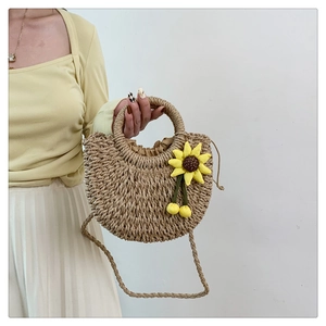 Detail der handgewebten Strohtasche mit gelbem Sonnenblumen-Dekor und Rundgriffen