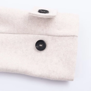 Detailed close-up of soft beige wool coat sleeve with two black round resin buttons