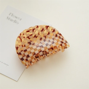 Detail of checkered acetate hair claw clip showing a large amber and beige polished finish