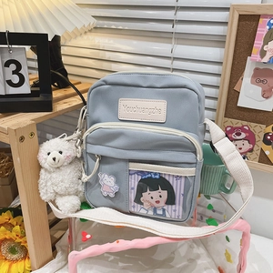 Vue détaillée du sac bandoulière en toile bleue avec un adorable porte-clés ours blanc