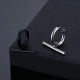 Detail of punk style stainless steel hoop earrings with hanging cylindrical pendant charms