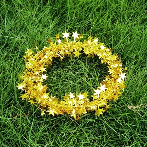 Macro detail of flexible gold star garland decoration on a festive lawn background