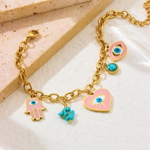 Gold chain bracelet with pink enamel heart, Hamsa hand, and turquoise charms on stone base