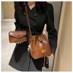 Détails du sac seau en cuir huilé marron et petite pochette avec bandoulière chaîne dorée