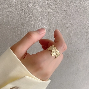 Detailed view of wide gold irregular lava texture ring styled with beige blazer cuff