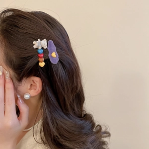 Detail of plush purple duckbill clip and white bear hairpin set worn on hair