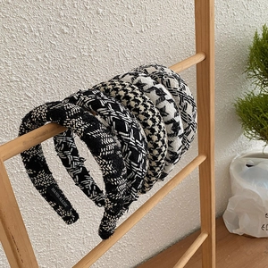 Close-up of five knitted tweed headbands with handmade labels on a wooden display