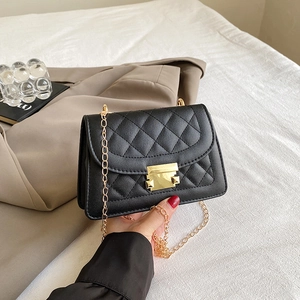 Detalle de bolso acolchado negro con correa de cadena dorada y hebilla metálica