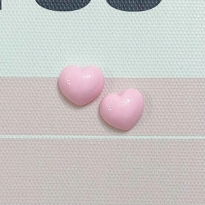 Detail of two glossy pink 3D resin heart charms on a striped fabric background