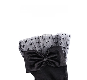 Detail of black bridal gloves featuring dotted mesh lace and a large satin bow accent