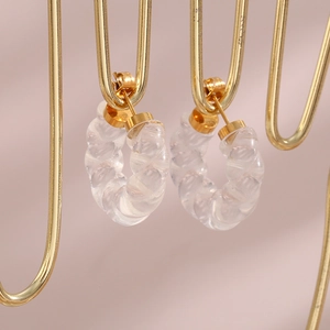Vue détaillée de boucles d'oreilles créoles torsadées en acrylique avec fermoirs dorés