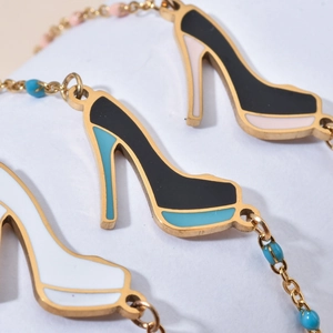 Macro detail of gold-tone chain bracelet with colorful stiletto heel charms and blue beads