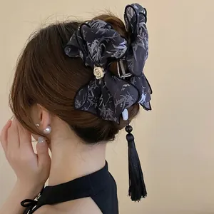 Pince à cheveux nœud en soie avec camélia doré et longs pompons noirs