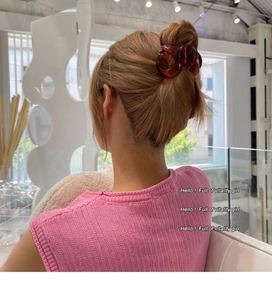 Vue de dos d'un modèle portant une grande pince à cheveux ambre en résine pour chignon