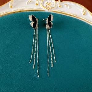 Silver butterfly tassel ear clip with black enamel and diamonds on velvet background