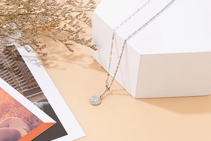 Detail of silver link chain with vintage coin pendant on white geometric blocks